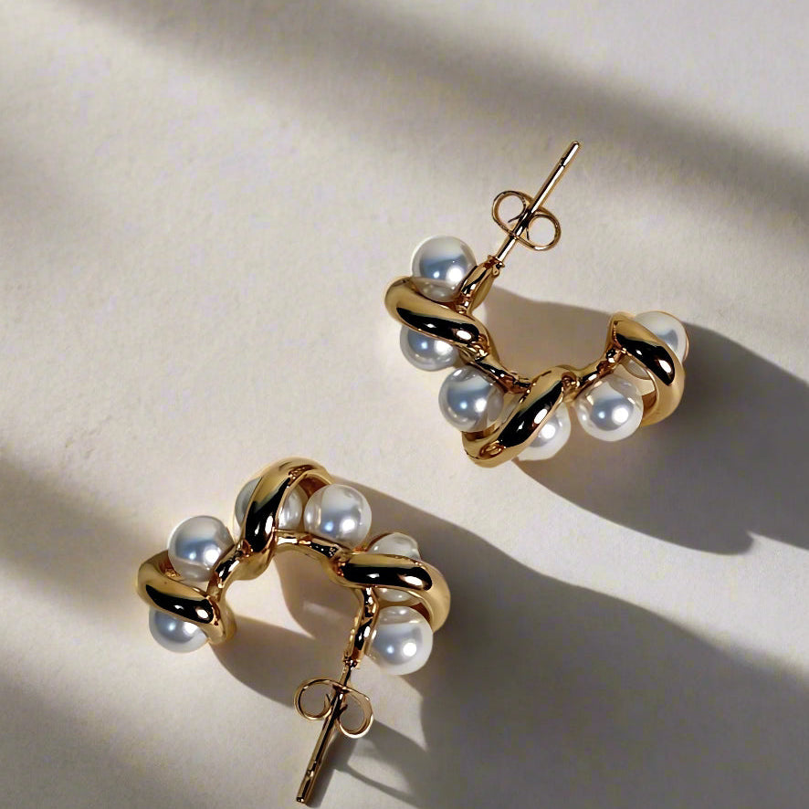 Gold and pearl earrings on a beige background