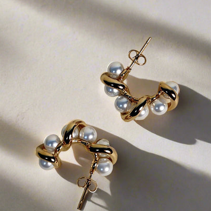 Gold and pearl earrings on a beige background