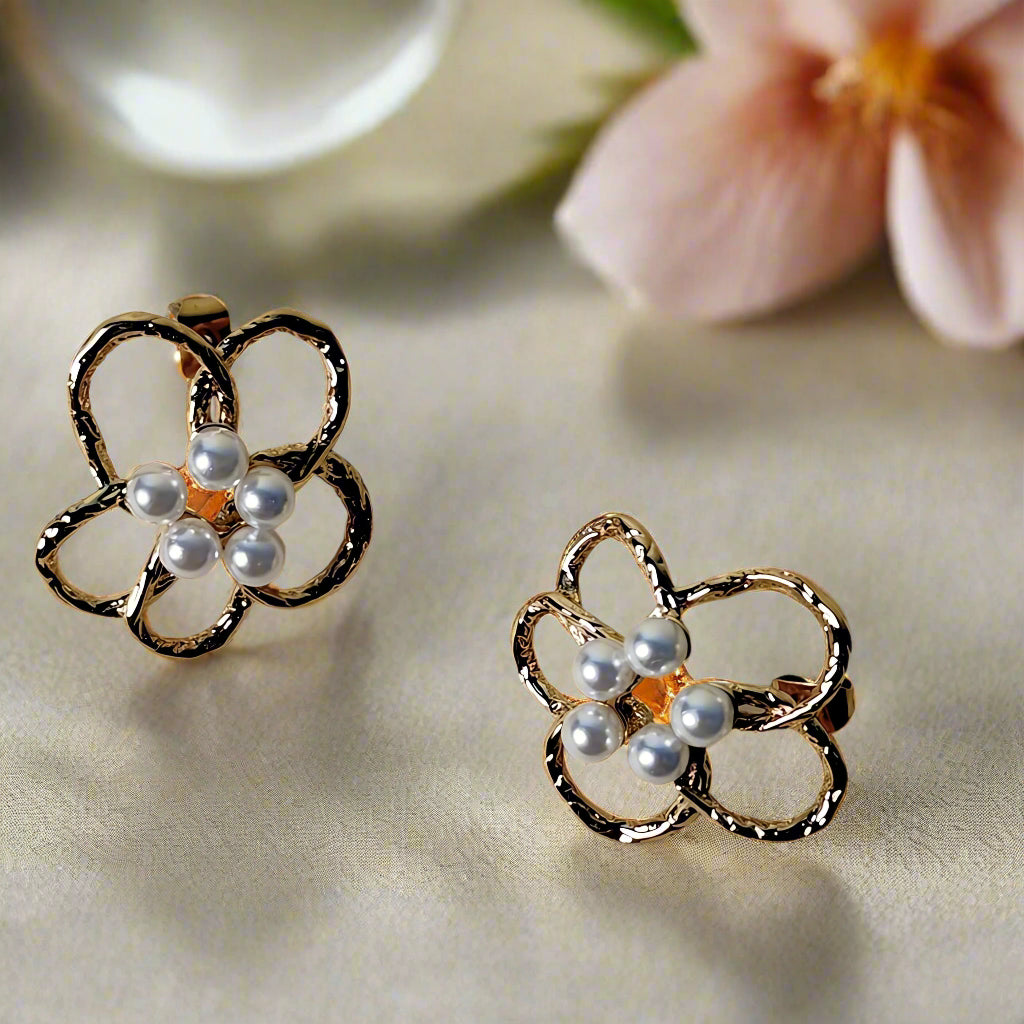 Pair of gold earrings with pearl-like stones on a beige background