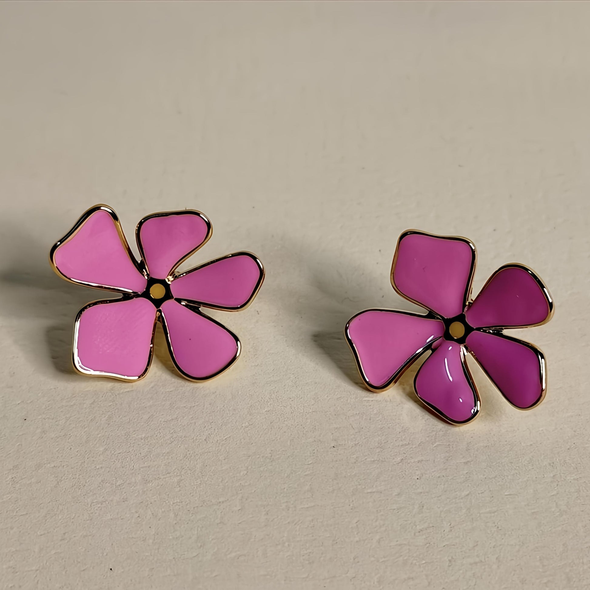 Pair of pink flower-shaped earrings on a beige background