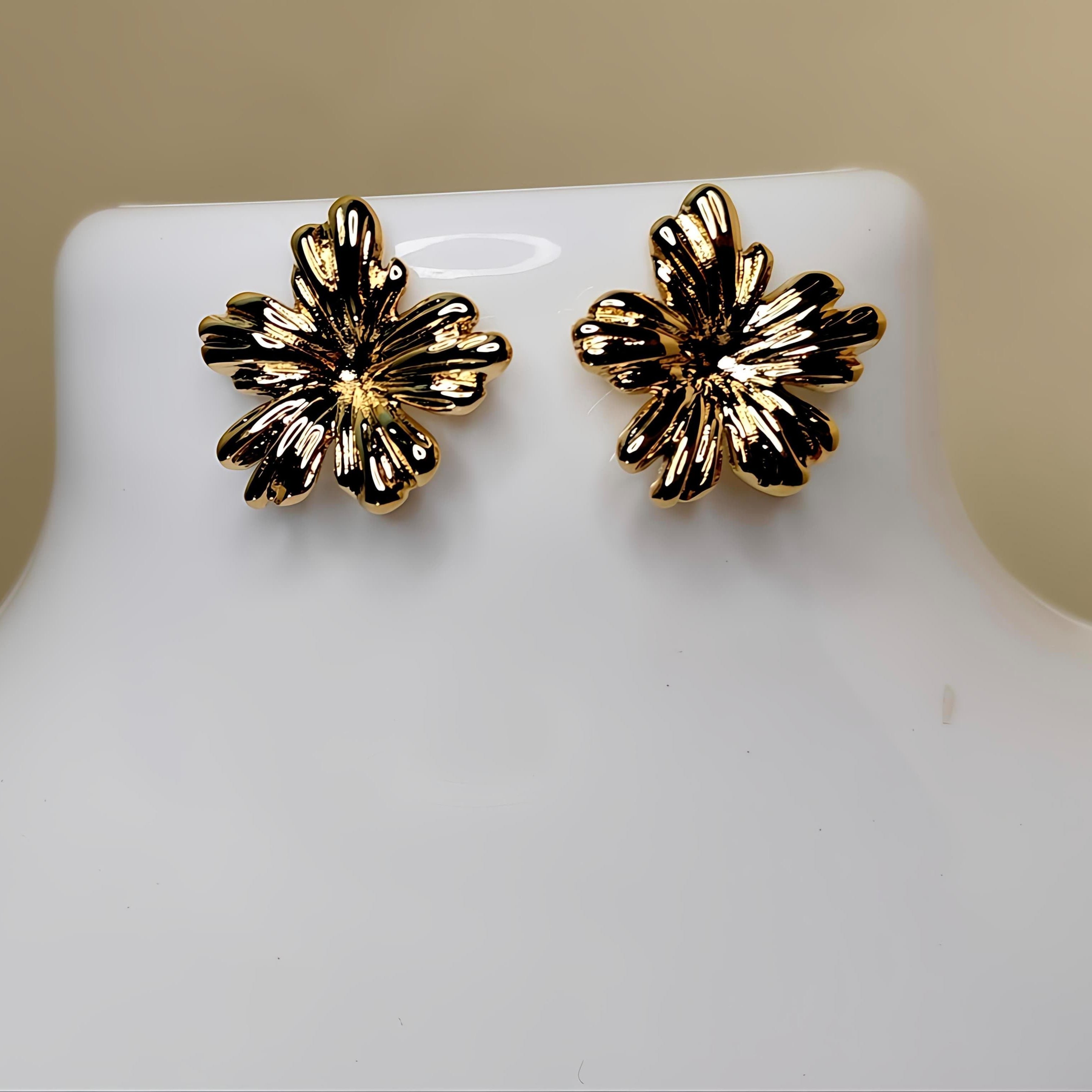 Gold floral earrings on a mannequin bust against a beige background
