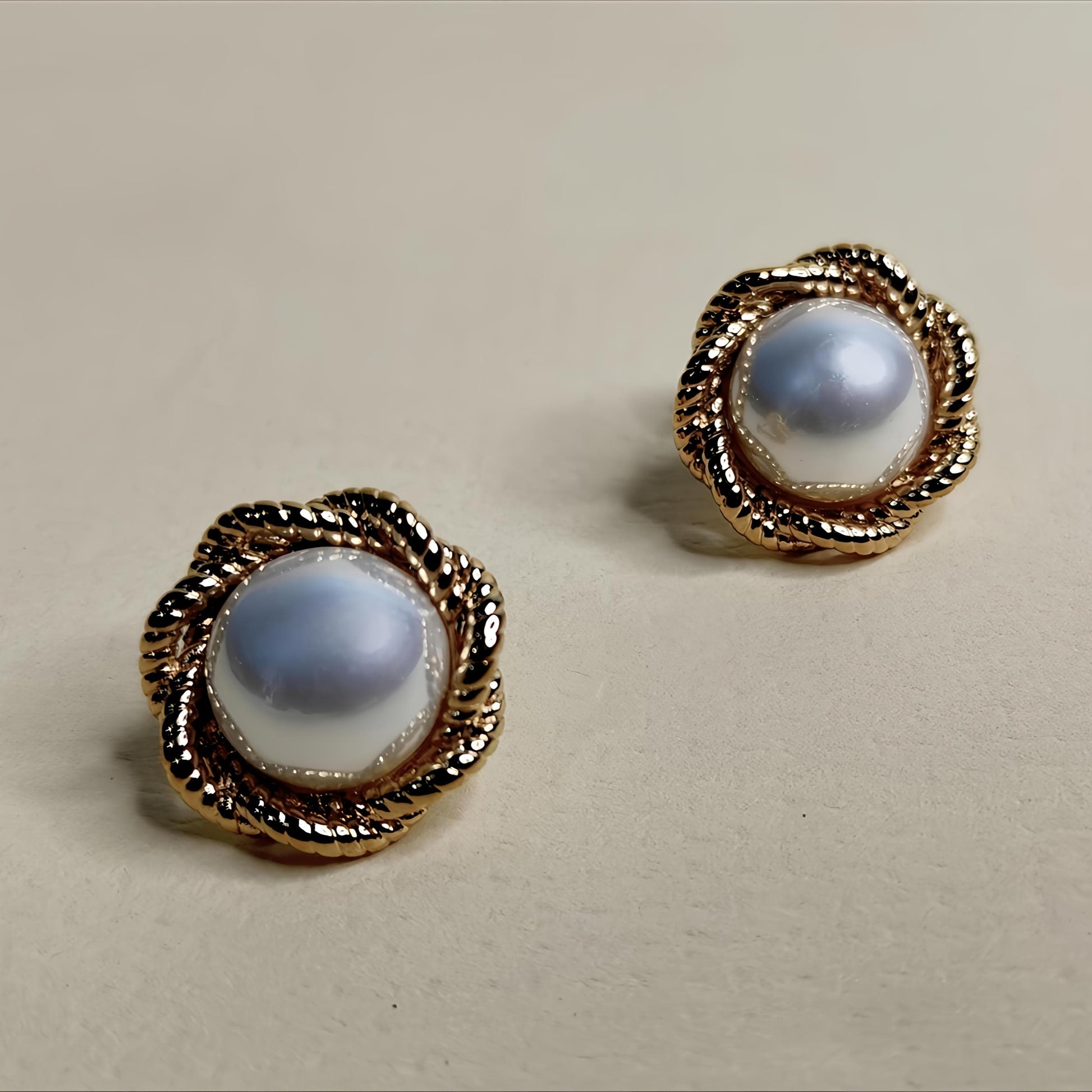 Pair of earrings with gold frames and blue gemstones on a beige background