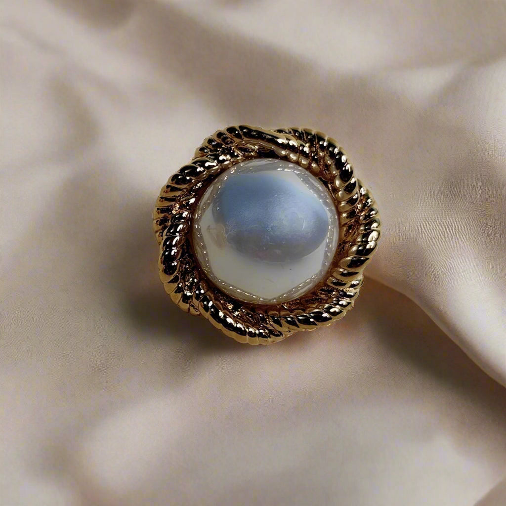 Pair of pearl earrings with gold accents on a beige background