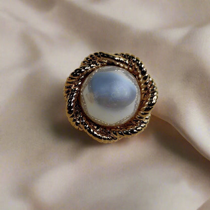 Pair of pearl earrings with gold accents on a beige background